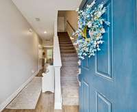 Stairs up to the bedrooms, hallway to the kitchen and living space with half bath for guests.