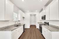 Modern galley kitchen with vented microwave, granite countertops, and undermount sink.