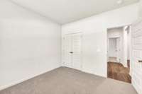 Comfortable secondary bedroom with neutral tones, plush carpet, and a double-door closet.