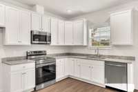 A classic, modern kitchen with crisp white cabinetry, granite countertops, an undermount sink, and a vented microwave. The clean lines and practical layout make it both stylish and highly functional—ready for everyday cooking or hosting with ease.