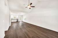 Bright, open-concept living space with vaulted ceilings and wood-look flooring. The airy layout flows seamlessly into the kitchen, creating the perfect setting for entertaining or relaxing. Modern finishes and natural light enhance the spacious feel.