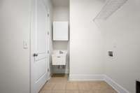 Tiled laundry room with a sink and extra storage.