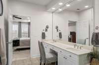 Primary bath features an oversized vanity with double sinks and a comfortable seated area.
