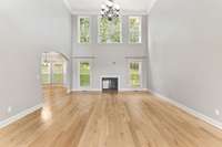 Living room with FP and a wall of windows providing abundant natural light and a sense of spaciousness.