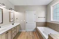 The primary bath has double vanities, a jacuzzi bath, linen closet and walk-in shower.