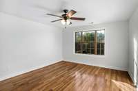 Secondary upstairs bedroom with unique ceiling lines and bright natural lighting.