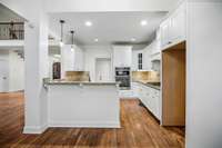 Bright, open kitchen with a large island, white cabinetry, and pendant lighting — perfect for gatherings and entertaining.