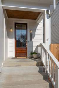 A covered front porch greets you as you walk up to the freshly stained front door.