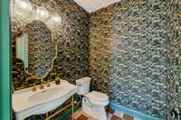Brass stand vanity, metallic floral wallpaper, and checked tile flooring create an exciting half bath