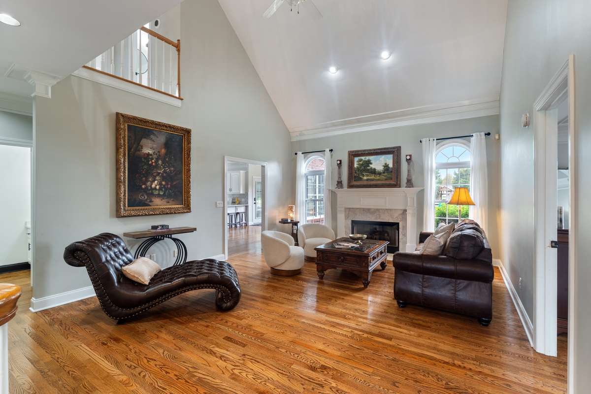 Spacious great room with vaulted ceilings, hardwood floors and fireplace framed by sunburst windows for abundant natural light.