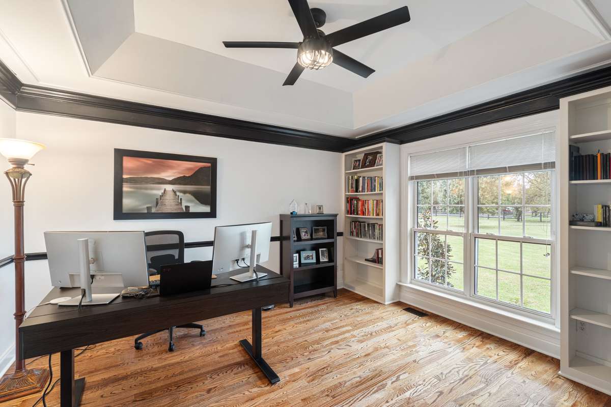 Office with built in bookshelves, tray ceiling and crown molding.