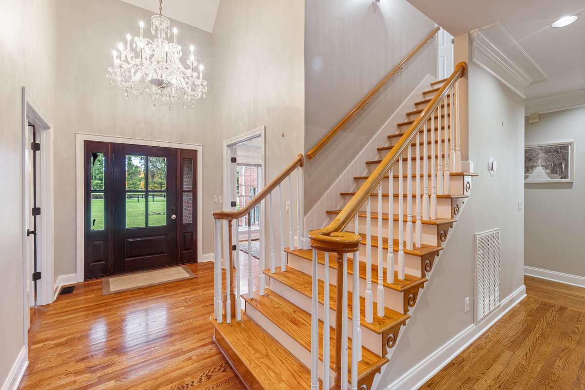 Step into this light filled entry with rich hardwood floors, a statement chandelier, and a beautiful staircase that sets the tone for the home’s timeless style