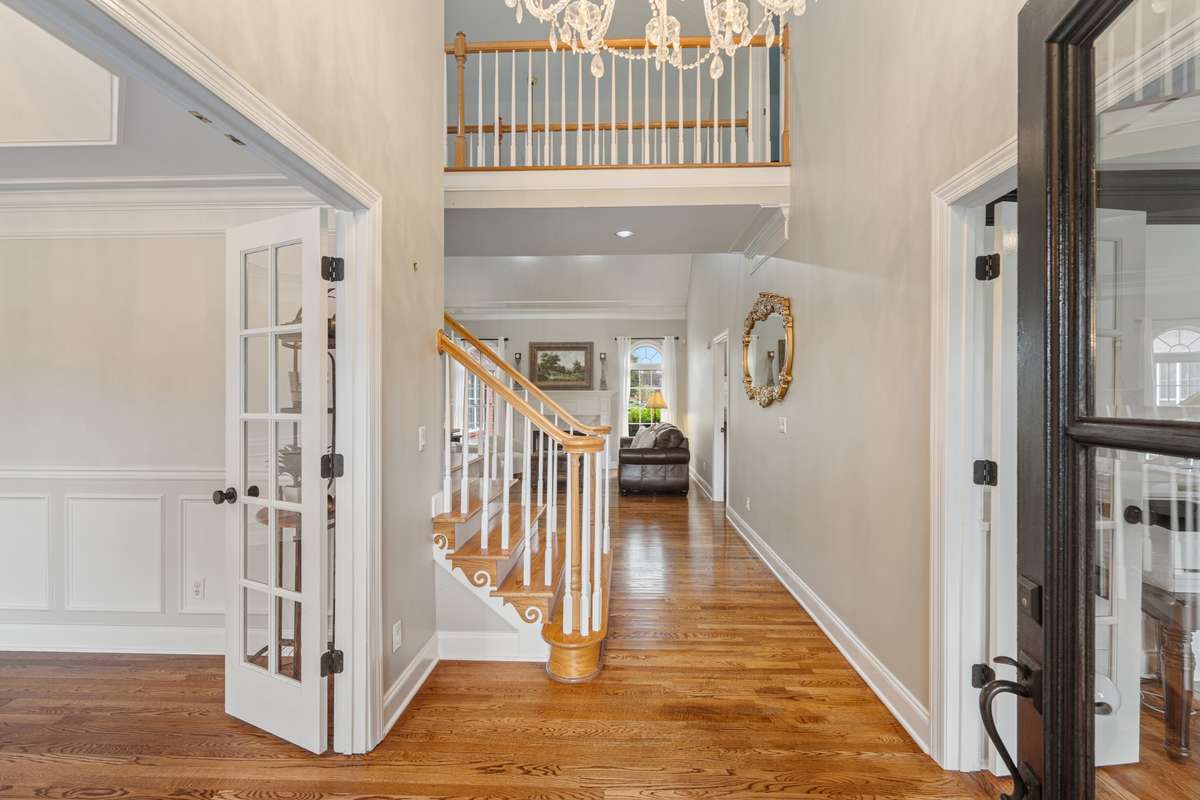 The two story foyer offers an open flow into the main living room while the dining room and living room flank the entry with glass french doors.