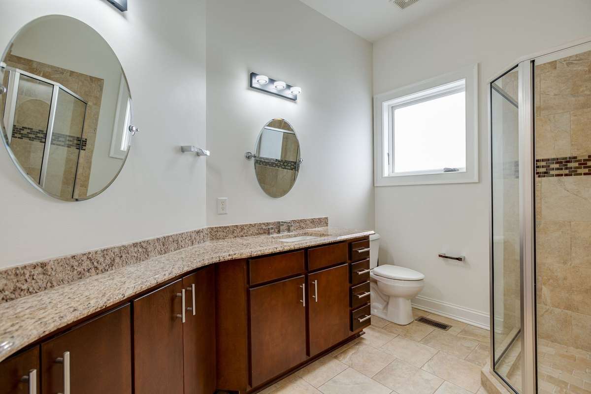 Bedroom 3 private full bath with ample cabinets/drawers and counterspace with tile surround walk-in shower.