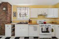 Notice the craftsman trimmed windows, the original brick detail, the striking sink, warm countertops, and adorable open shelving!