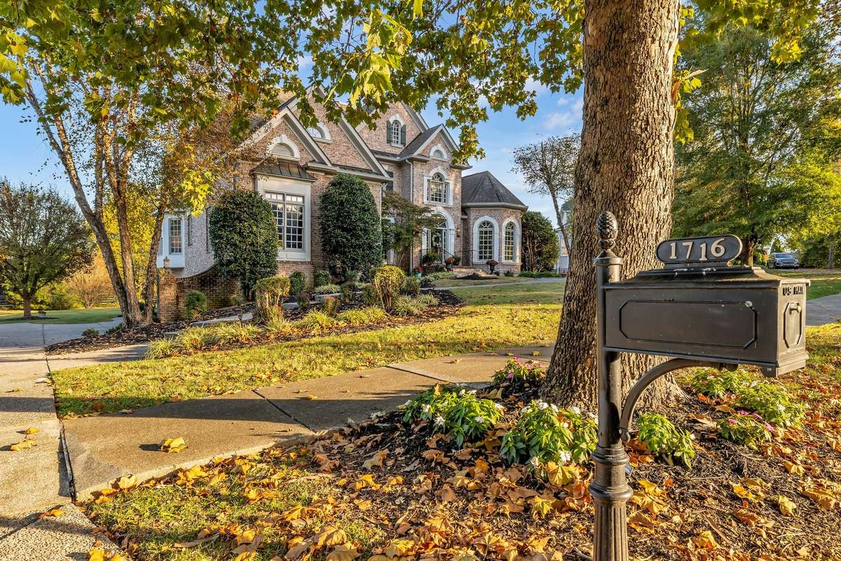 Extended driveway and landscaped approach lead to a three-car garage and rear access