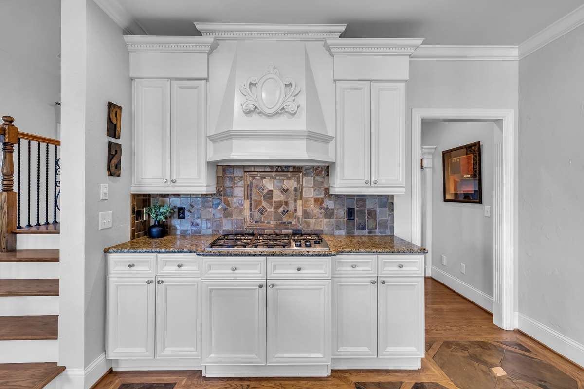 Beautifully detailed tile backsplash and decorative range hood create a true focal point.