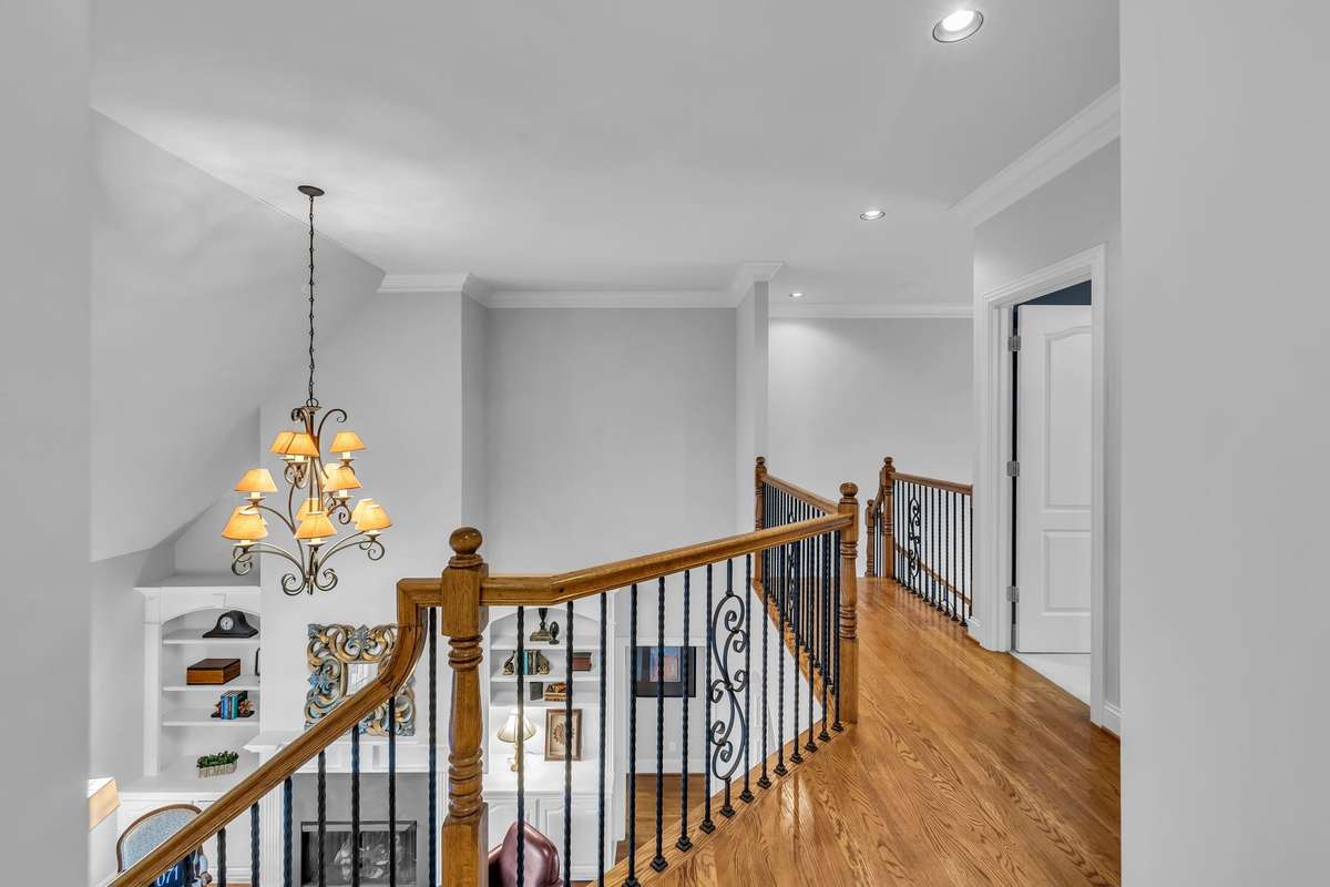 Open landing with wrought-iron railings overlooks the living area below—airy and architectural.