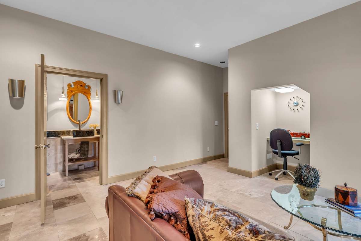 Comfortable gathering space with neutral tones, recessed lighting, and access to a stylish full bath. Built in computer desk