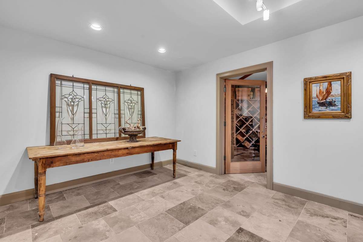 Adjacent tasting room highlighted by designer lighting and glass-paneled entry to the cellar.