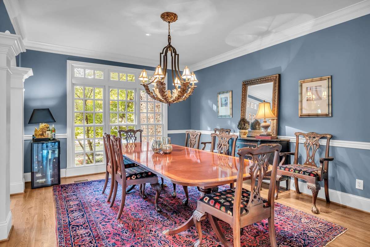 Elegant formal dining room with crown molding, designer chandelier, and walls of windows for natural light.