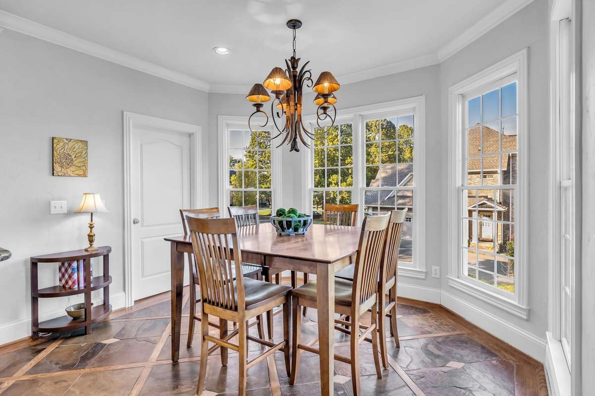 Sunlit breakfast nook surrounded by windows overlooking the landscaped yard.