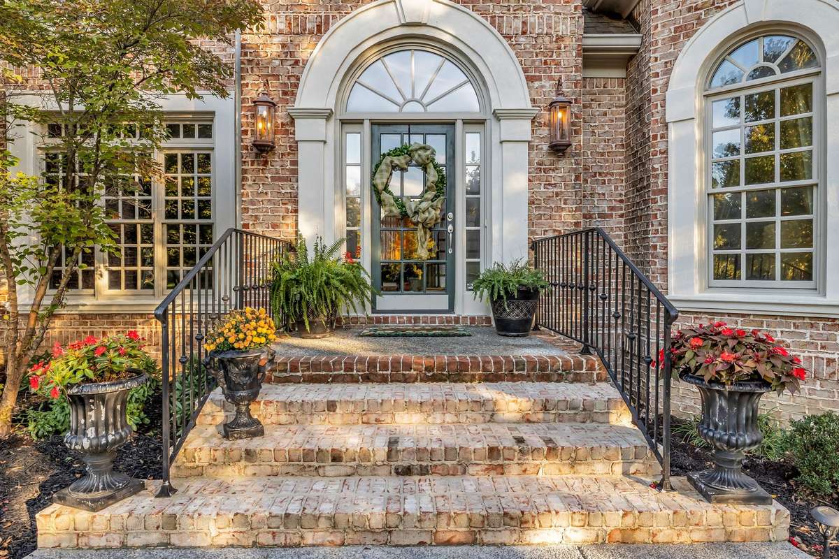 Charming brick steps and wrought-iron railings welcome guests to a gracious front entry.