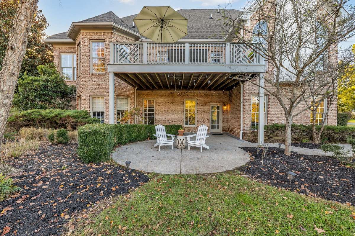 Inviting lower patio offers shaded outdoor seating surrounded by lush landscaping.
