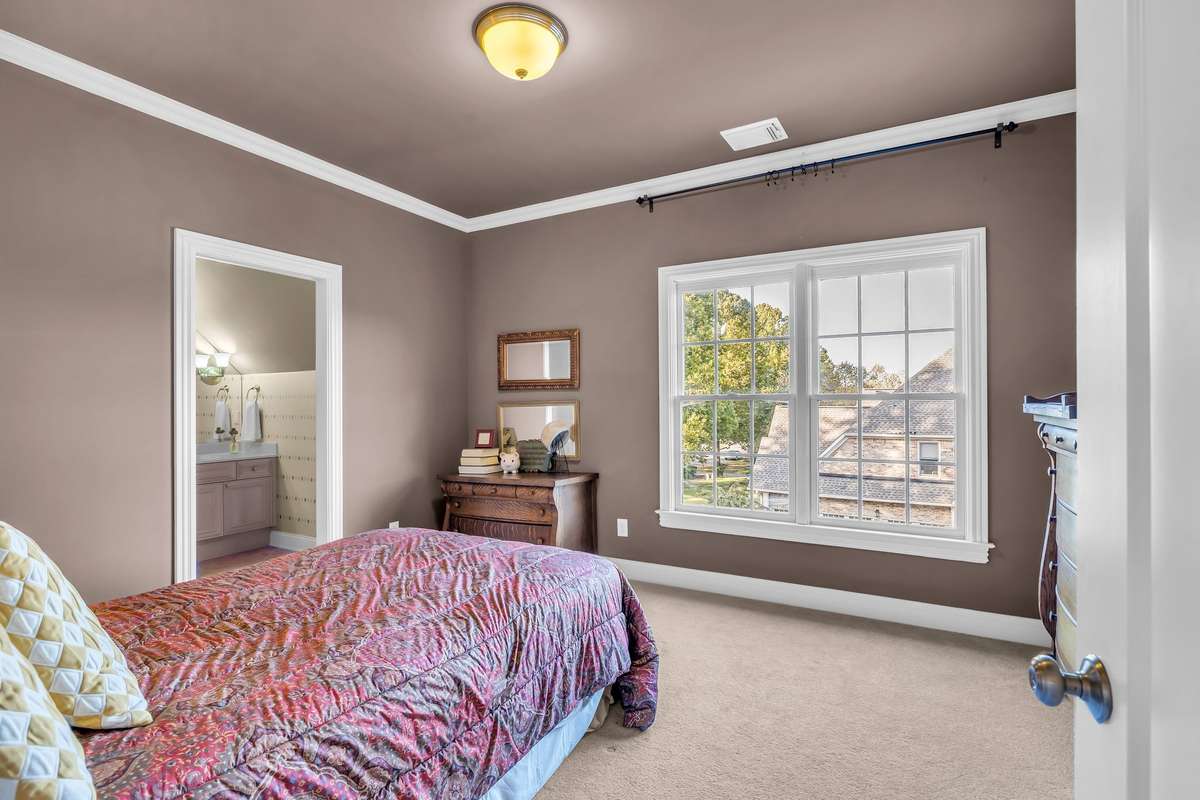 Sunlit guest suite featuring crown molding and peaceful neighborhood views. Private Bath Attached