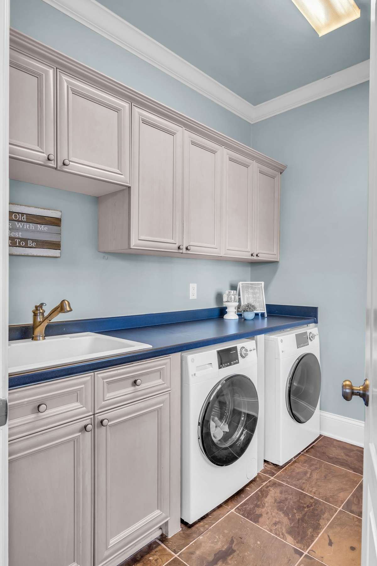 Efficient laundry room with upper cabinetry, utility sink, and built-in storage.