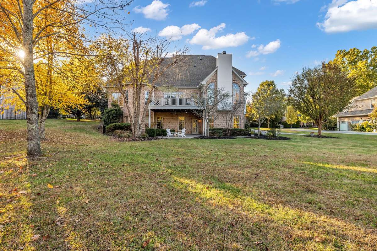 Back exterior showcases the home’s tiered deck, brick detail, and expansive windows.