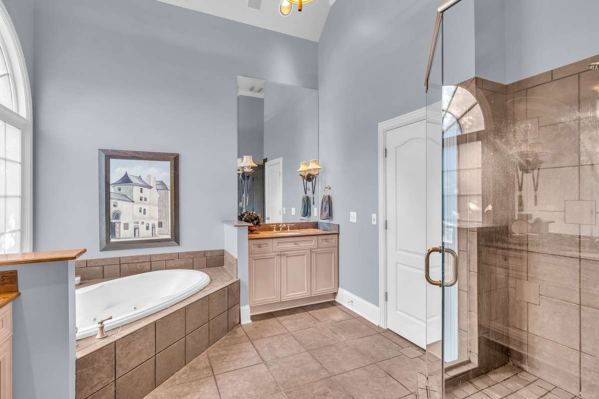 Spacious glass-enclosed shower complements the timeless tile and upscale fixtures.