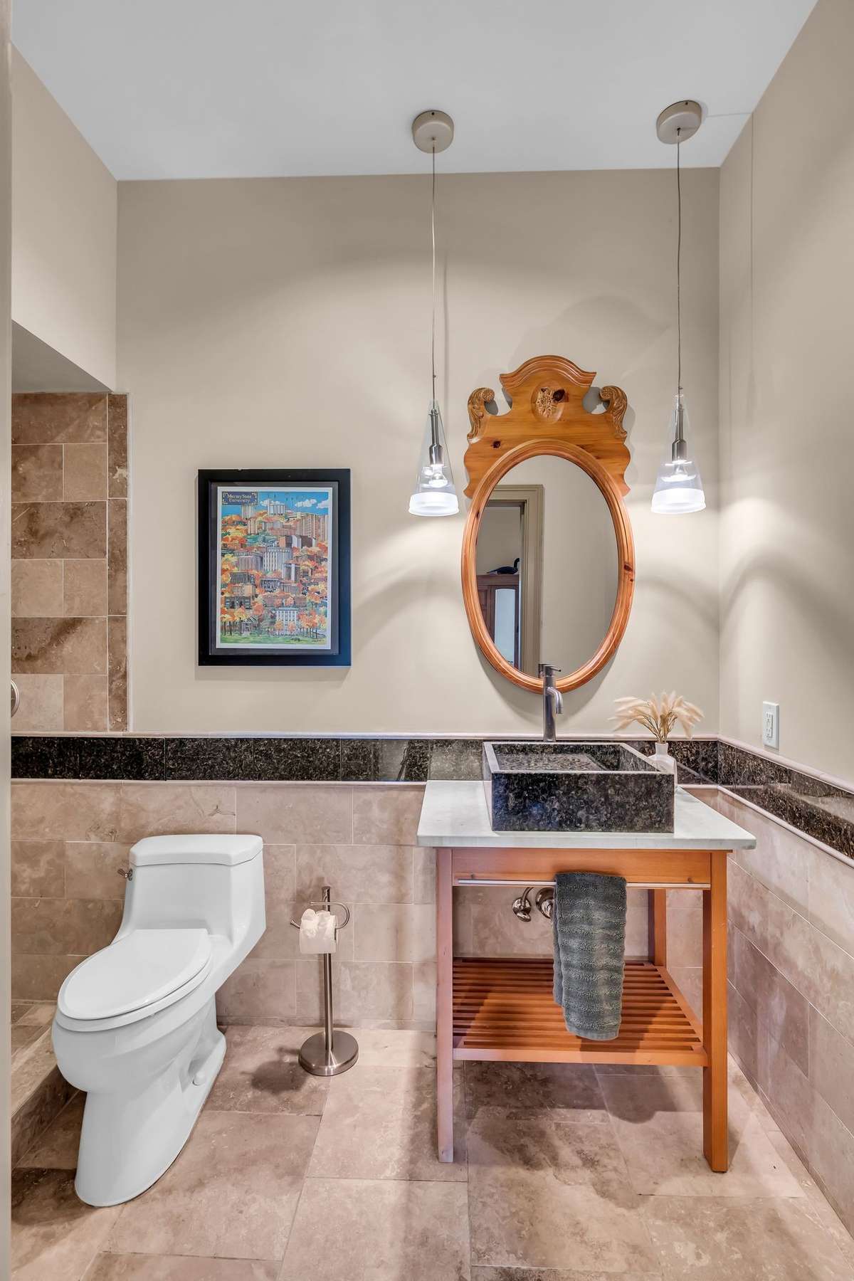 Chic full bath featuring a custom vanity with stone sink, pendant lighting, and warm tile surround.