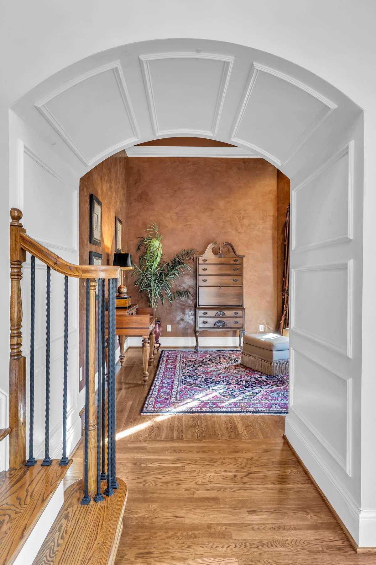 Arched entry leads to a richly styled home office or sitting room with designer wall finish and natural light.
