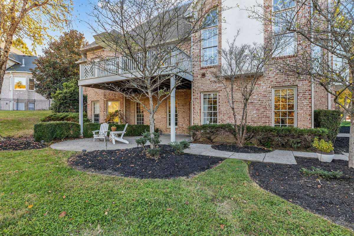 Timeless brick architecture with tiered deck and covered patio offering seamless indoor-outdoor living.