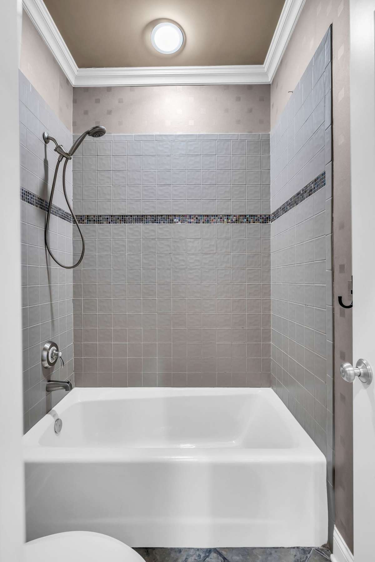 Elegant tile surround with accent border and crown molding—bright and beautifully finished.