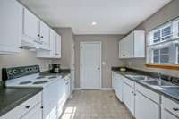 Another kitchen view, showing the counter space and cabinets and the door leading to the laundry room
