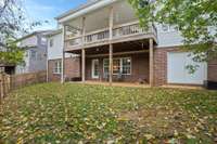 Rear view of home and backyard with privacy fence.  Covered patio on lower level and covered deck off main level