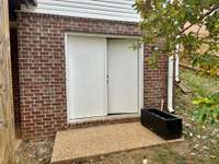 Double doors lead into unfinished storage room. . . just the right space to store your lawn mower, yard tools and more.  Would make a great workshop!