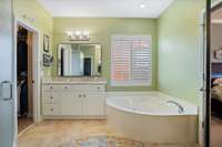 Luxurious primary bathroom with ceramic tile floor, whirlpool tub, separate vanities with new countertops and mirrors.