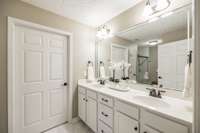 The primary bathroom is beautifully appointed with double sinks, offering plenty of counter space and ample storage underneath for added convenience.