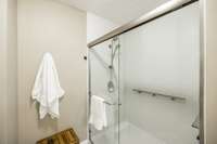 A large, tiled walk-in shower with sleek glass doors adds a touch of luxury.