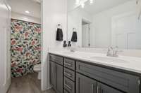 Positioned between the two secondary bedrooms, this bathroom offers convenience for multiple users, with a dividing door separating the double vanity from the shower and commode area.