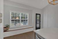 Bright, inviting kitchen with spacious island, ample counter space and classic subway tile.  A built in bench sits just beneath the window to provide extra seating for the eat-in kitchen.