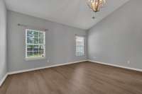 This inviting master suite showcases elegant LVP flooring and a stunning vaulted ceiling that enhances the room's sense of space and light.  Large windows offer a serene view overlooking the fenced, flat backyard--perfect for pets to play safely