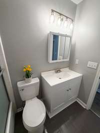 new vanity, new light fixture, new toilet, new mirror with medicine cabinet, freshened updated tile floor