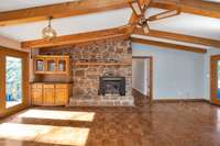 Den- wood flooring, vaulted ceiling with exposed beams, ceiling fan, fireplace
