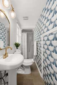 Guest bathroom design elevated with stylish and playful wallpaper detail.