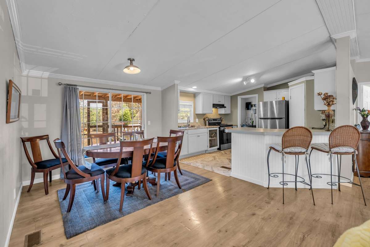 This home features a generously sized dining area that provides an ideal setting for gatherings and dinner parties. Conveniently situated adjacent to the kitchen, this space seamlessly extends outdoors with direct access to a covered porch