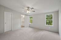 Bright primary bedroom with new carpet, ceiling fan, and private ensuite bathroom.